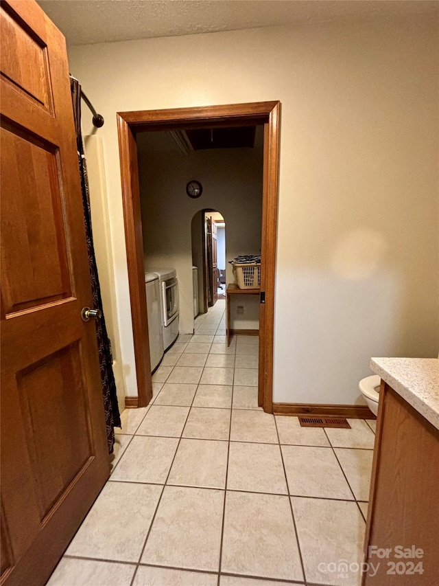 corridor featuring separate washer and dryer and light tile patterned flooring