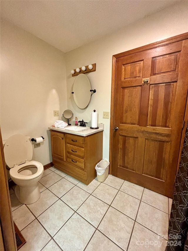 bathroom with a textured ceiling, tile patterned flooring, vanity, and toilet