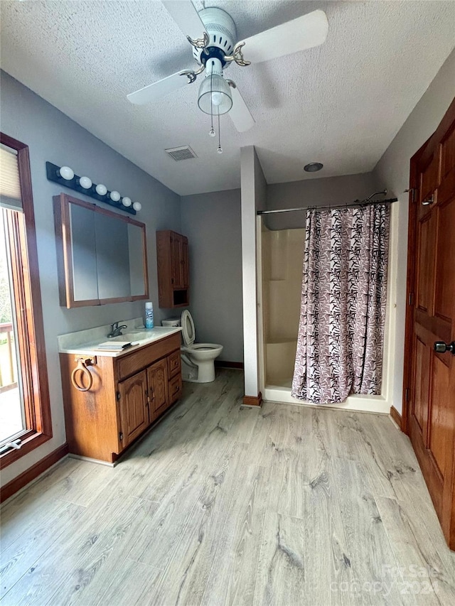 bathroom with hardwood / wood-style floors, curtained shower, ceiling fan, vanity, and toilet