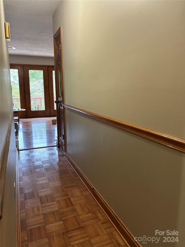 corridor featuring dark parquet floors and a textured ceiling