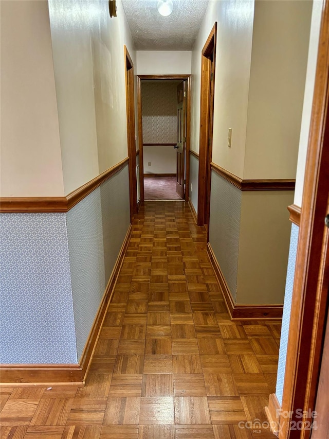 hall featuring a textured ceiling and dark parquet flooring