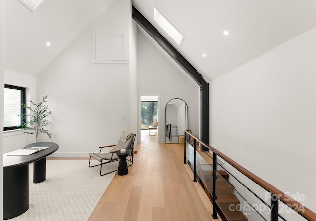 interior space with high vaulted ceiling, light hardwood / wood-style floors, a skylight, and plenty of natural light