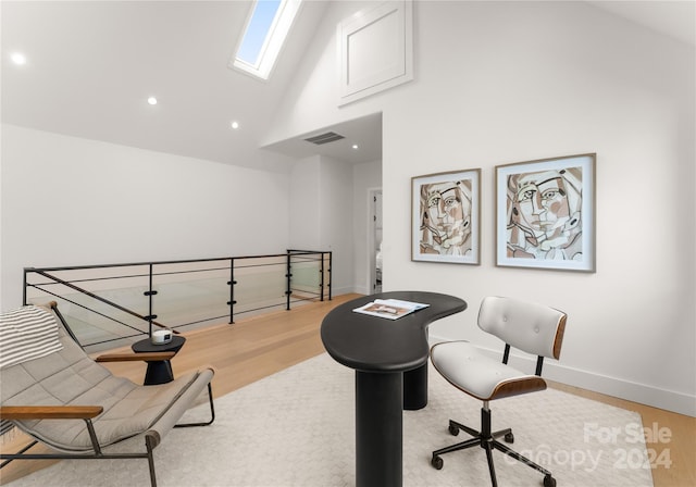 office with a skylight, light wood-type flooring, and high vaulted ceiling