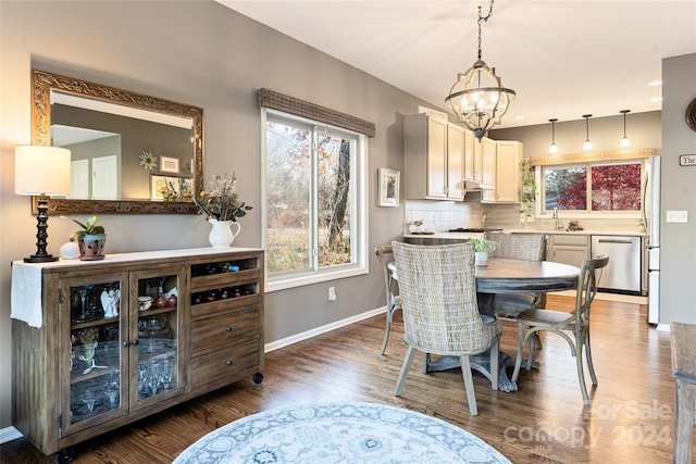 dining space with a notable chandelier, dark wood-type flooring, and sink