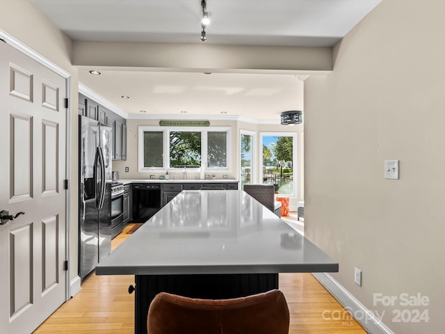 kitchen featuring stainless steel appliances, light hardwood / wood-style floors, a center island, and a breakfast bar area