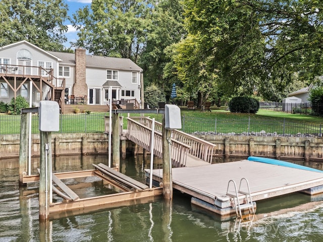 view of dock with a yard and a deck with water view