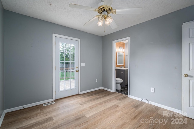 interior space with ceiling fan, a textured ceiling, light hardwood / wood-style flooring, and ensuite bathroom