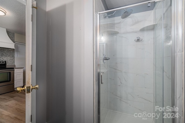 bathroom with a textured ceiling, hardwood / wood-style flooring, an enclosed shower, backsplash, and vanity