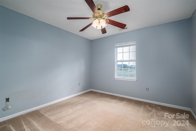 unfurnished room with ceiling fan, a textured ceiling, and carpet