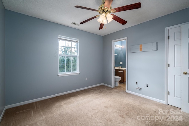 unfurnished bedroom featuring ceiling fan, sink, a textured ceiling, light colored carpet, and ensuite bath