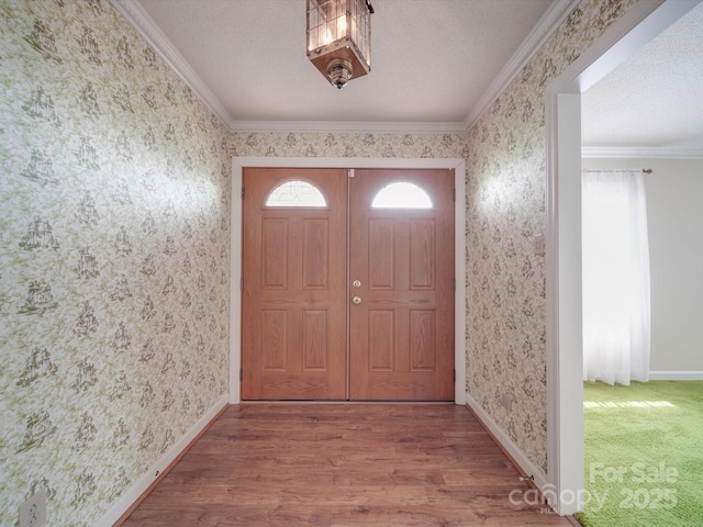 entryway featuring wood-type flooring, ornamental molding, and a textured ceiling