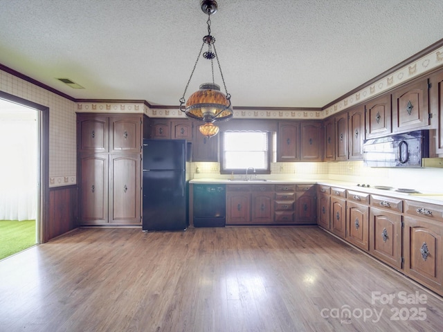 kitchen featuring pendant lighting, sink, light hardwood / wood-style flooring, black appliances, and a textured ceiling