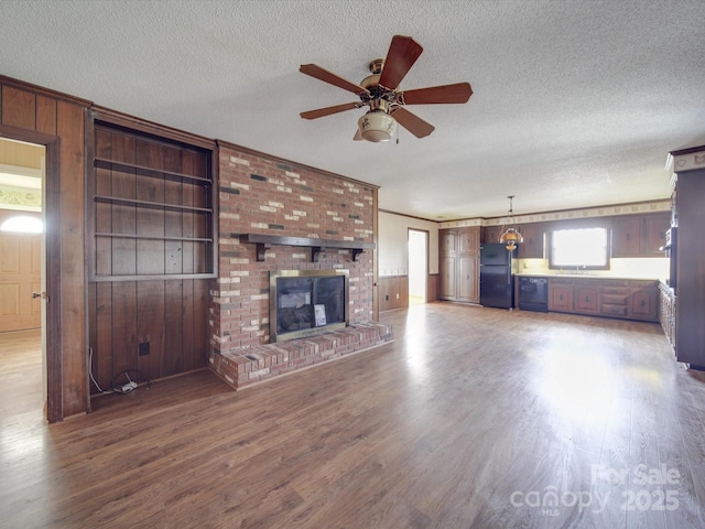 unfurnished living room with a brick fireplace, dark hardwood / wood-style floors, a textured ceiling, and wood walls