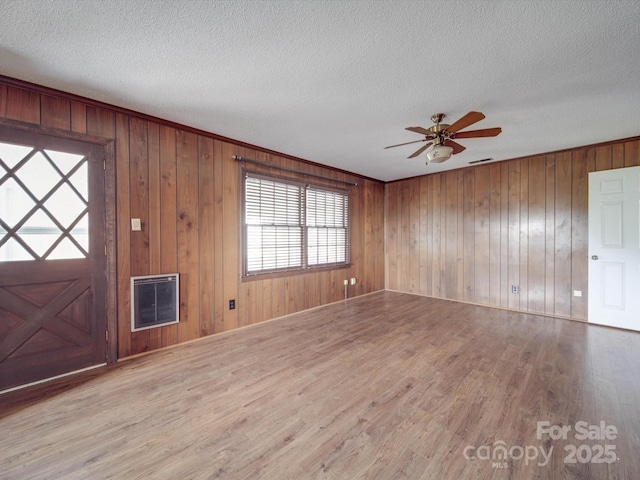 foyer featuring heating unit, light hardwood / wood-style flooring, a textured ceiling, and wood walls