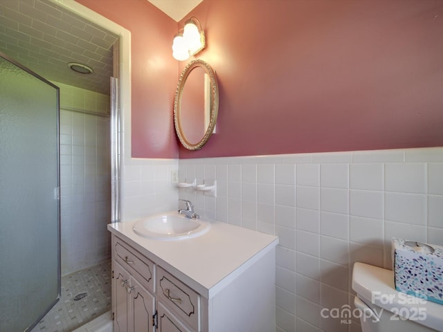 bathroom featuring toilet, tile walls, vanity, and a shower with shower door