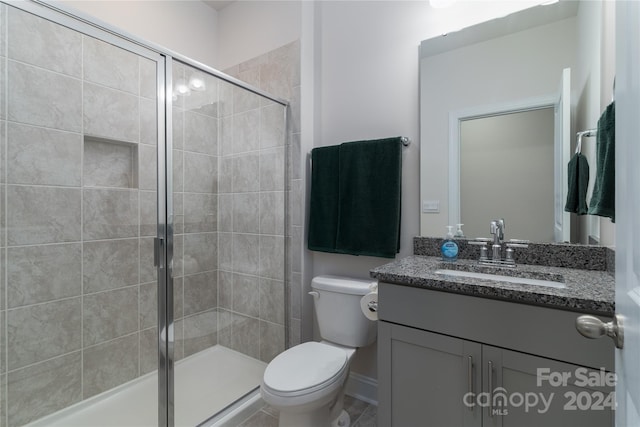 bathroom featuring vanity, a shower with shower door, and toilet