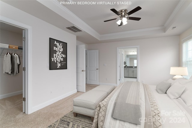 carpeted bedroom featuring a spacious closet, a closet, a tray ceiling, ceiling fan, and ensuite bath