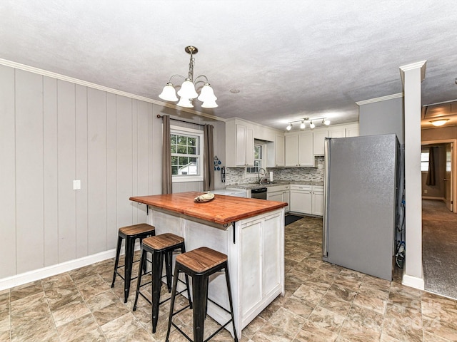 kitchen featuring decorative light fixtures, backsplash, a chandelier, appliances with stainless steel finishes, and a center island