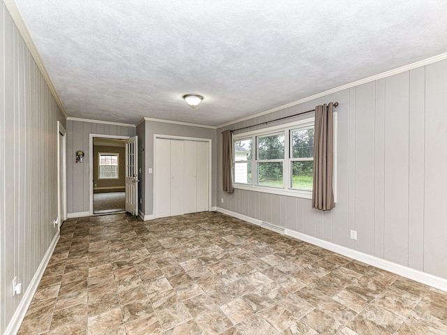 interior space with a textured ceiling, a closet, crown molding, and wood walls