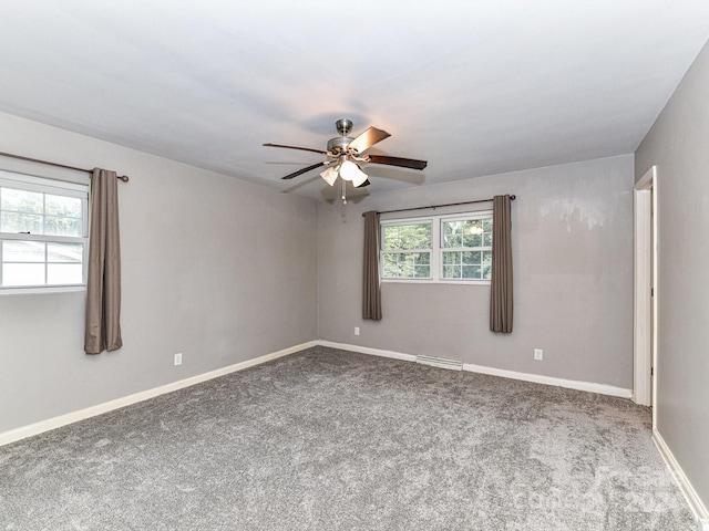 carpeted spare room featuring ceiling fan and plenty of natural light