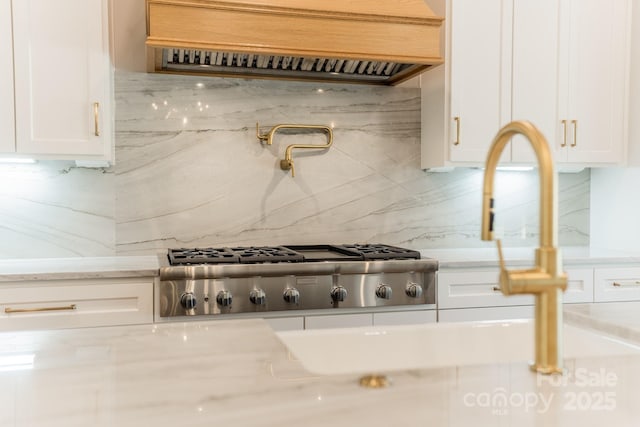 kitchen with light stone counters, tasteful backsplash, stainless steel gas cooktop, and white cabinets