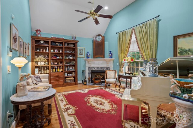 interior space with ceiling fan, hardwood / wood-style floors, vaulted ceiling, and a high end fireplace