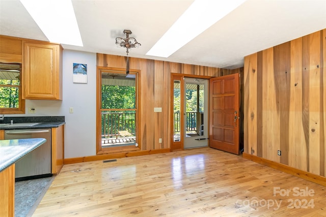 kitchen featuring light hardwood / wood-style flooring, wood walls, a skylight, and a healthy amount of sunlight