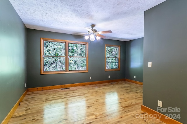 spare room with light hardwood / wood-style floors, ceiling fan, and a textured ceiling