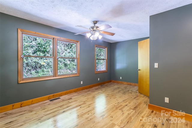 spare room with light wood-type flooring, ceiling fan, and a textured ceiling