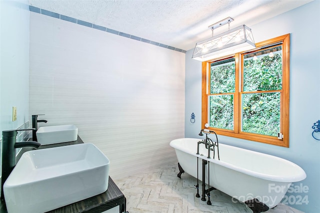 bathroom with tile walls, a tub to relax in, vanity, parquet flooring, and a textured ceiling