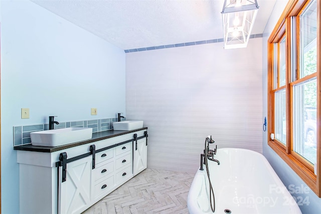 bathroom with a bath, vanity, parquet flooring, and a wealth of natural light