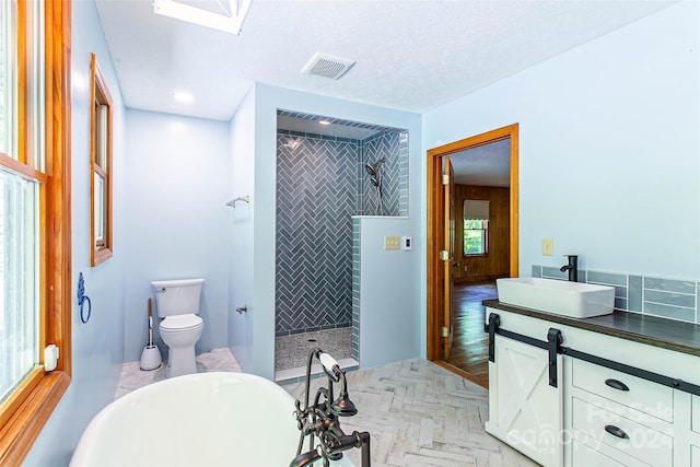 full bathroom featuring independent shower and bath, vanity, toilet, and a textured ceiling