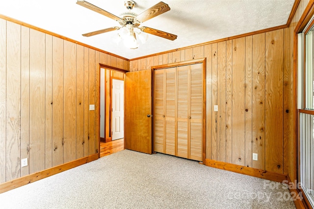 unfurnished bedroom with crown molding, carpet flooring, wood walls, and ceiling fan