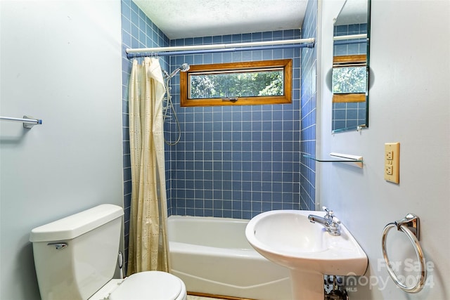 full bathroom featuring shower / tub combo with curtain, a textured ceiling, sink, and toilet