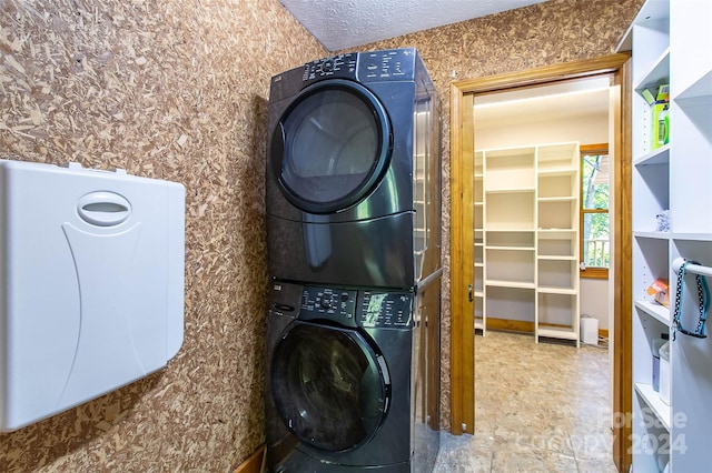 washroom with a textured ceiling and stacked washer / drying machine