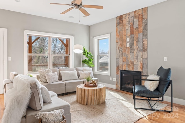 living room with a tile fireplace, hardwood / wood-style flooring, and ceiling fan