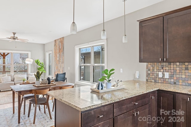 kitchen featuring light stone countertops, kitchen peninsula, decorative backsplash, and a healthy amount of sunlight