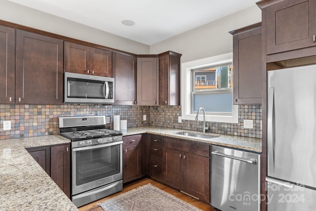 kitchen featuring light stone countertops, stainless steel appliances, tasteful backsplash, and sink