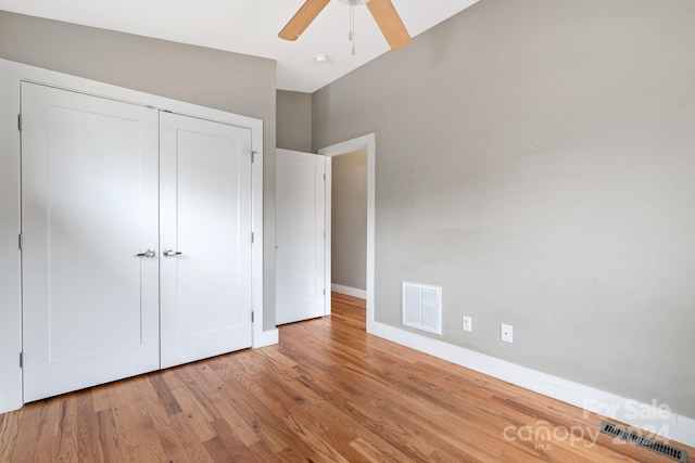 unfurnished bedroom featuring ceiling fan, vaulted ceiling, light wood-type flooring, and a closet