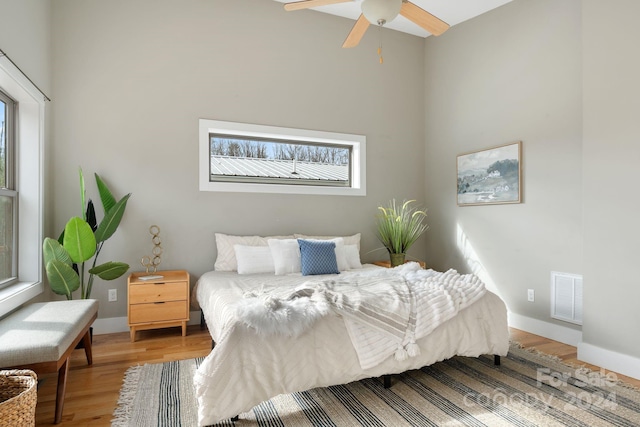 bedroom featuring multiple windows, ceiling fan, and hardwood / wood-style floors