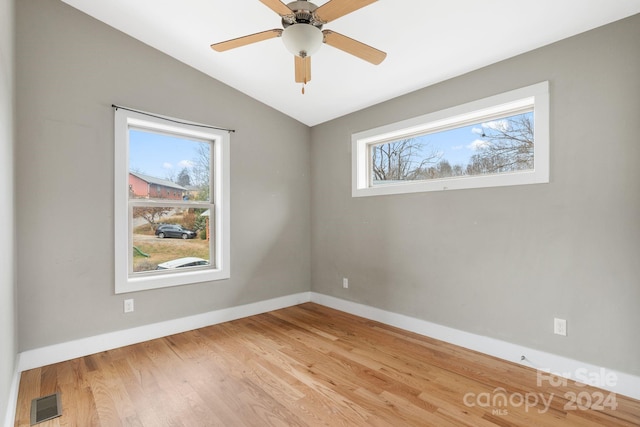 empty room featuring wood-type flooring, vaulted ceiling, and plenty of natural light