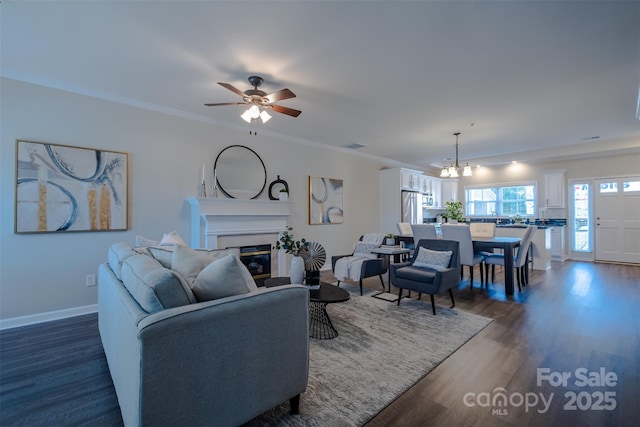 living room featuring ornamental molding, dark wood-type flooring, and ceiling fan with notable chandelier