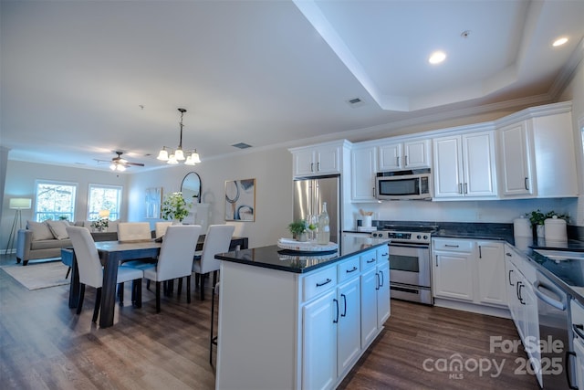 kitchen with a kitchen island, appliances with stainless steel finishes, decorative light fixtures, white cabinetry, and dark wood-type flooring