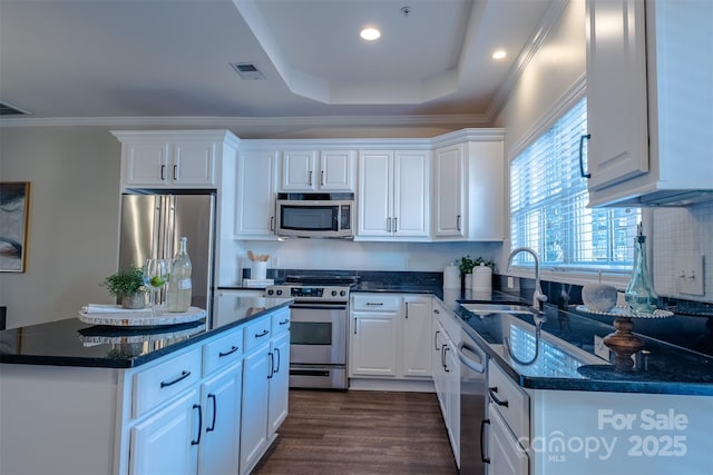 kitchen with appliances with stainless steel finishes, sink, white cabinets, a raised ceiling, and dark wood-type flooring