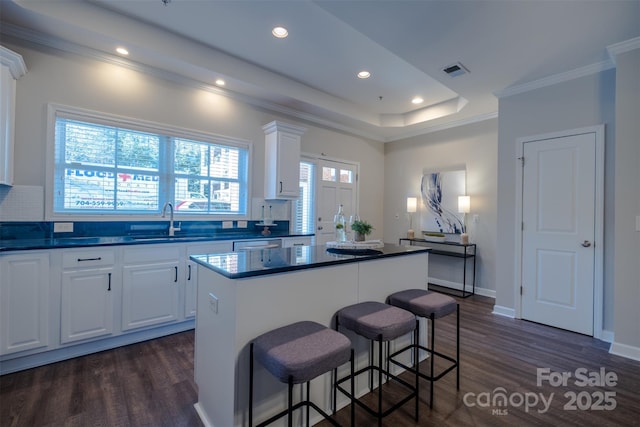 kitchen featuring white cabinetry, sink, dark hardwood / wood-style flooring, a center island, and crown molding