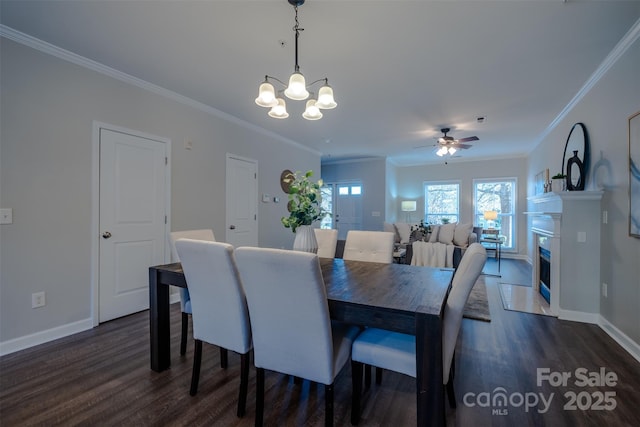 dining area with dark wood-type flooring, crown molding, and ceiling fan with notable chandelier