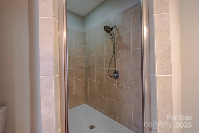 bathroom with a shower with shower door and toilet