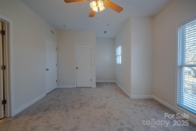 unfurnished bedroom featuring ceiling fan, light colored carpet, and multiple windows