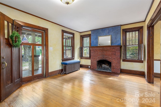 unfurnished living room with radiator, ornamental molding, a fireplace, and light hardwood / wood-style floors