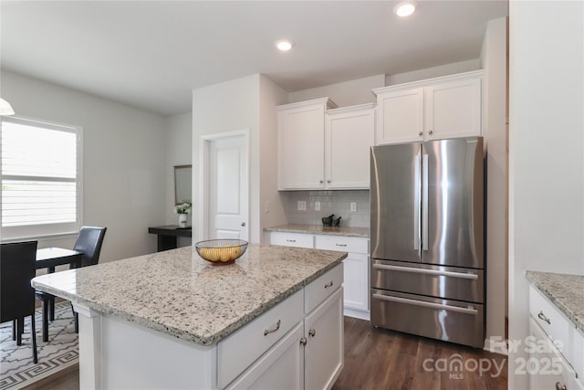 kitchen with white cabinetry, backsplash, a kitchen island, and stainless steel refrigerator